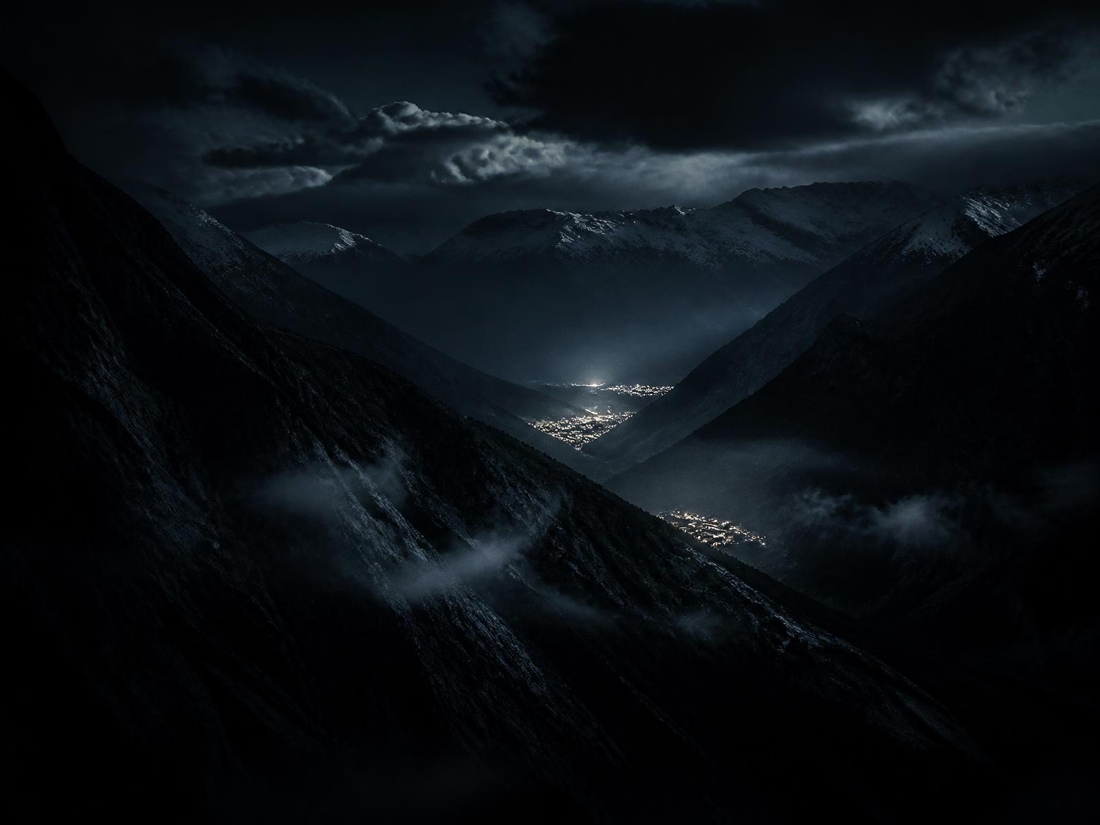Aerial view of a dark Himalayan valley with distant village lights